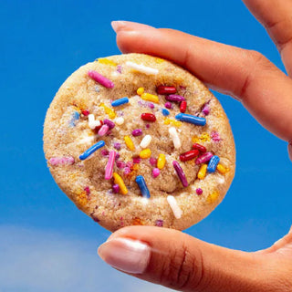 Hand holding a baked Sweet Loren's Birthday Cake cookie with colorful sprinkles