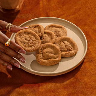Hand reaching for baked Sweet Loren's Pumpkin Spice cookies on a plate