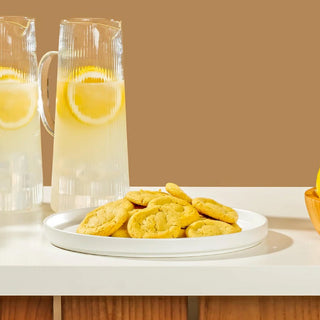 Plate of baked Sweet Loren's Lemon cookies next to a pitcher of lemonade